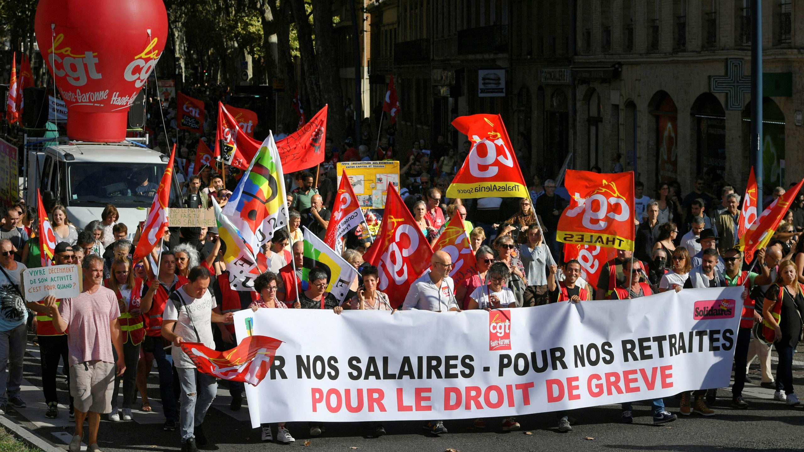 Protesters march behind a banner which reads as «For our wages, for our pensions, for the right to strike» during a demonstration in Toulouse, southwestern France, on October 18, 2022, after the CGT and FO trade unions called for a nationwide strike for higher salaries, and against the government’s requisitioning of fuel refineries to force some strikers back into opening fuel depots. – Unions in other industries and the public sector have also announced action to protest against the twin impact of soaring energy prices and overall inflation on the cost of living. (Photo by Valentine CHAPUIS / AFP)