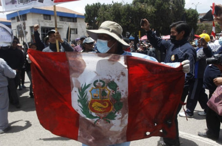 A demonstrator with a Peruvian flag walks with relatives and friends of the victims of clashes with the Peruvian police carrying their coffins in the Andean city of Juliaca, southern Peru, on January 11, 2023. – Peru’s prosecutor’s office on the eve opened an inquiry against President Dina Boluarte and others for their role in the repression of anti-government protests that have seen at least 40 killed since December. (Photo by Juan Carlos CISNEROS / AFP)
