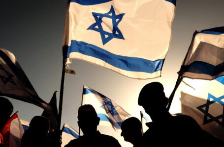 Israeli military veterans wave national flags during a rally against the government’s judicial reform bill, along a highway near Netanya on March 28, 2023. (Photo by JACK GUEZ / AFP)